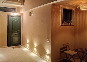 A hallway with a door, a bench, and a small window with plants. - La Casina in Massa: a house for 6 with parking, near the beach (Massa)