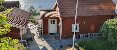 Une maison en bois avec un toit rouge, un petit porche et une vue sur un lac.