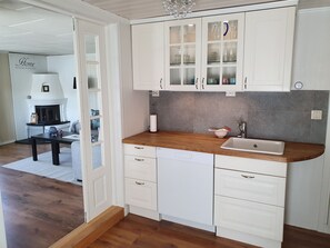 A modern kitchen with white cabinetry, a wooden countertop, and a built-in dishwasher.