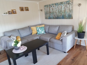 A modern living room with a grey sectional sofa, a black coffee table, and a painting on the wall.
