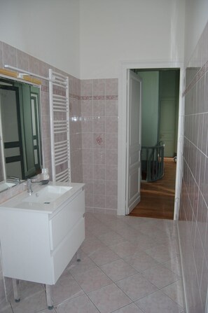 A bathroom with a white vanity, a mirror, and a shower area.
