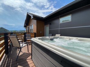 Ein Whirlpool auf einer Holzterrasse mit Blick auf ein Gebäude im Hintergrund.