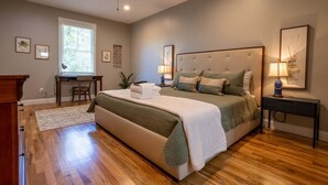 Quarto com uma cama grande, uma escrivaninha e uma cadeira.