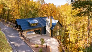 A modern house with a sloped roof, large windows, and a covered driveway. - Balsam Mountain Tree House | Luxury Retreat | Golf & Exclusive Club Amenities (Sylva)