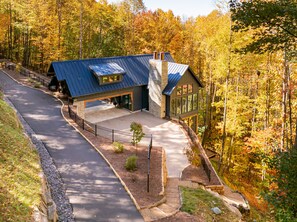 A modern house with a sloped roof, large windows, and a covered driveway. - Balsam Mountain Tree House | Luxury Retreat | Golf & Exclusive Club Amenities (Sylva)