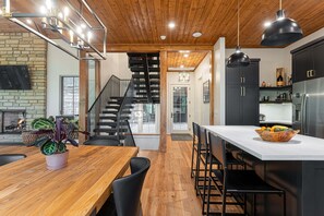 Une cuisine moderne dotée d’un îlot central, de meubles de couleur noire et d’un plafond en bois.