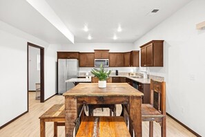 A modern kitchen with wooden cabinets, a stainless steel refrigerator, and a granite countertop.