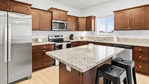 A modern kitchen with granite countertops, stainless steel appliances, and wooden cabinetry. - Cheney Home | Close to Interstate & Airport (Cheney)