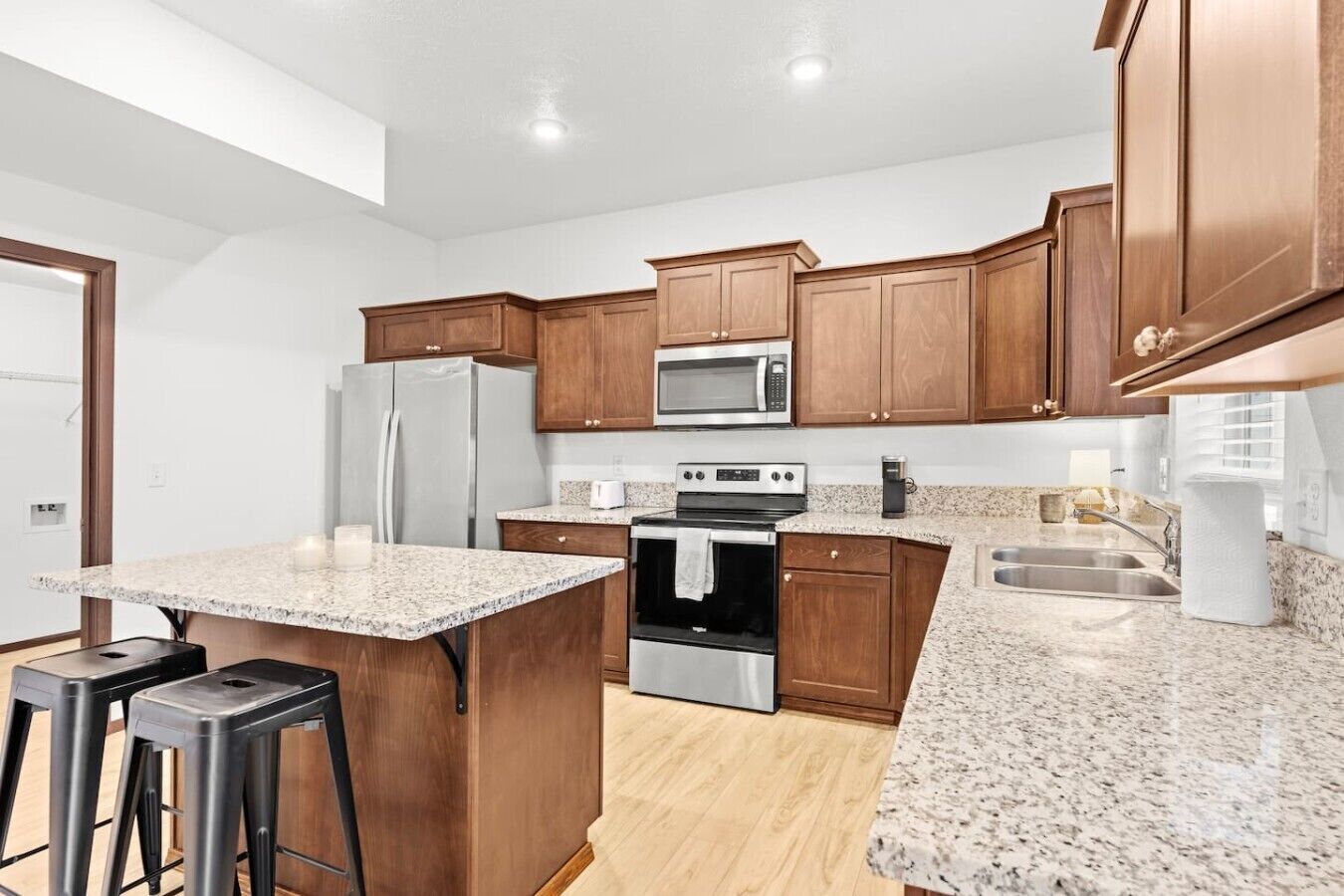 A kitchen with wooden cabinets, a granite countertop, a refrigerator, an oven, a microwave, and a sink.