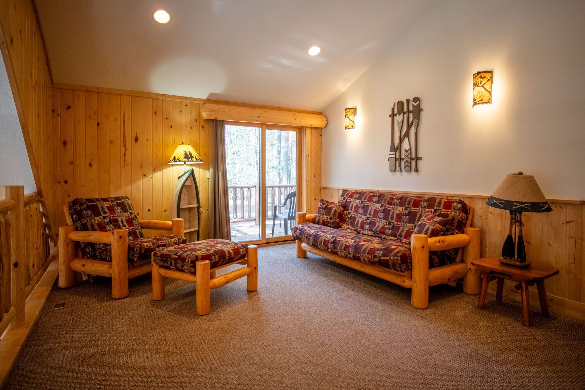 A wooden interior with a sofa, chairs, and a lamp.