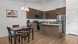 Una cucina moderna con mobili in legno, elettrodomestici in acciaio inossidabile e un'area pranzo con tavolo e sedie.