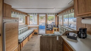 Een compact camperinterieur met een kitchenette, een zithoek met banken en een stuurconsole.