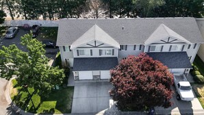 A two-story residential building with a garage, a driveway, and a large tree in front. - Cozy Coeur d’Alene Townhome (Coeur d`Alene)