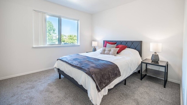 A bedroom with a bed, a nightstand, a window, and a ceiling light. - Cozy Coeur d’Alene Townhome (Coeur d`Alene)