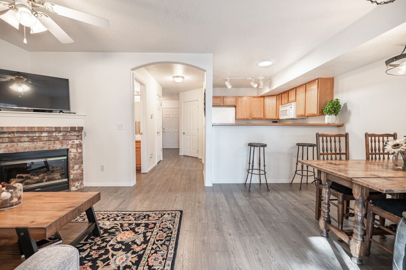 A modern kitchen with wooden cabinets, a built-in microwave, and a dining area with a wooden table and chairs.