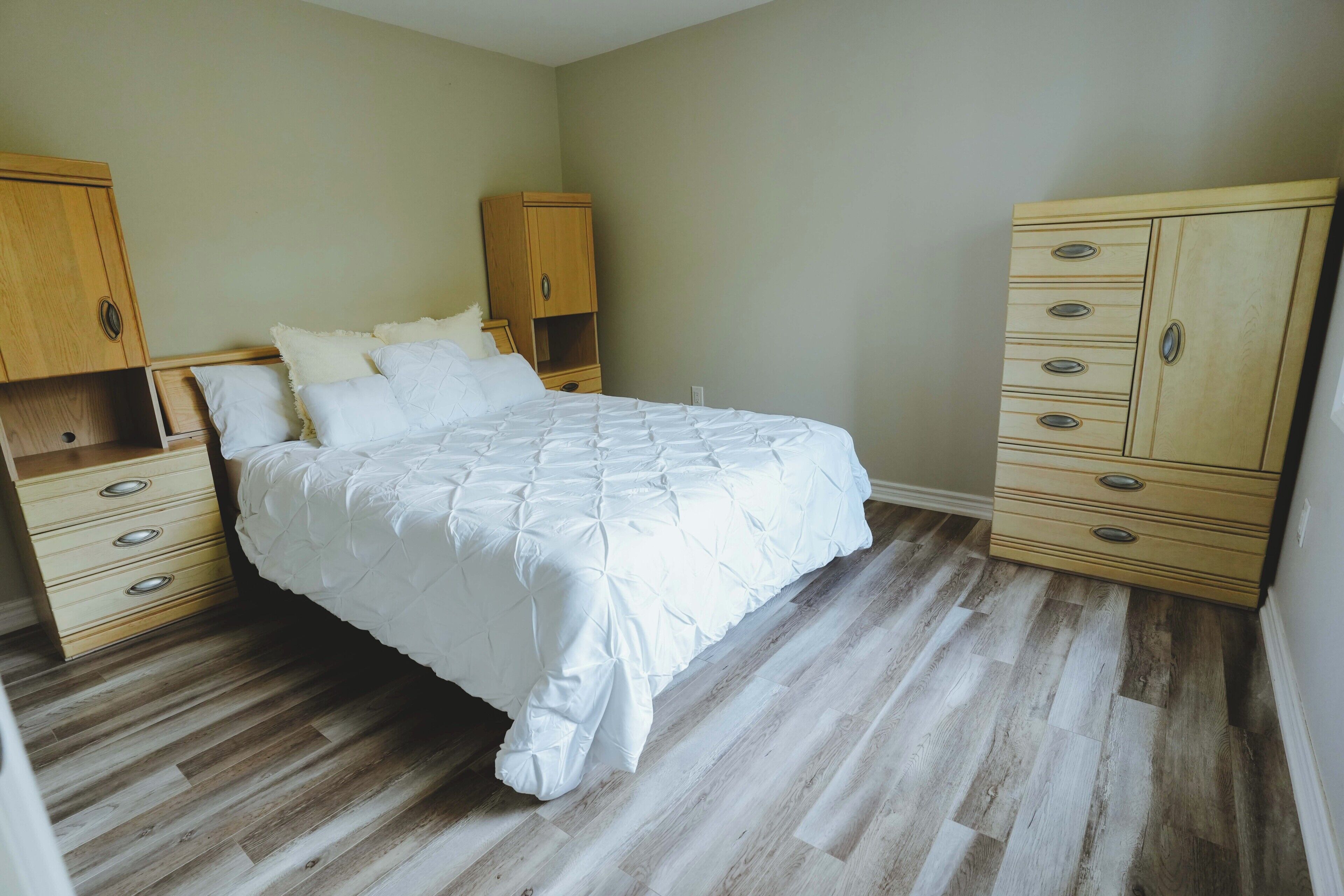 Une chambre à coucher avec un lit, une armoire en bois et une commode.