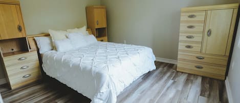 Une chambre à coucher avec un lit, une armoire en bois et une commode.