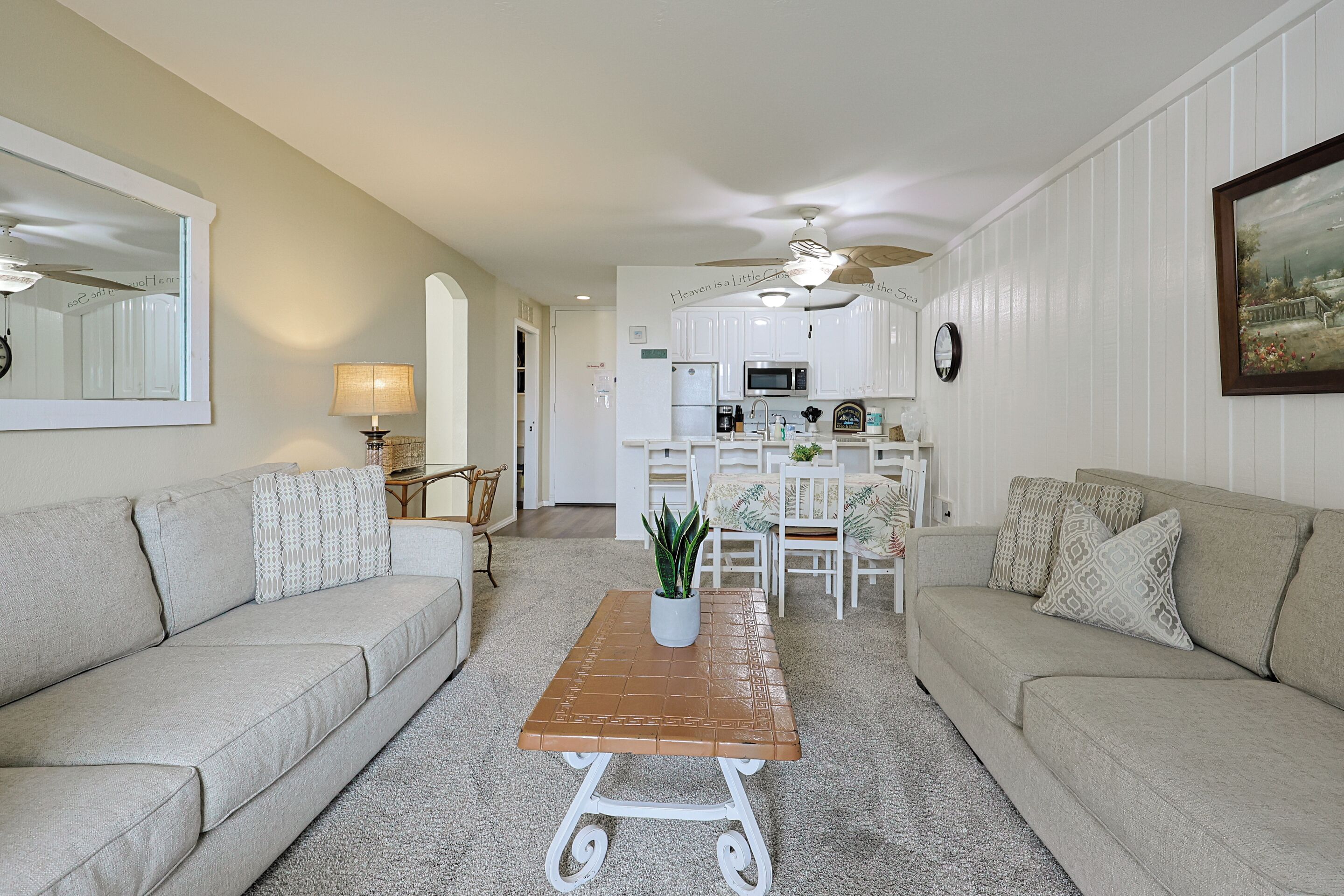 A living room with a sofa, a coffee table, and a kitchen in the background.