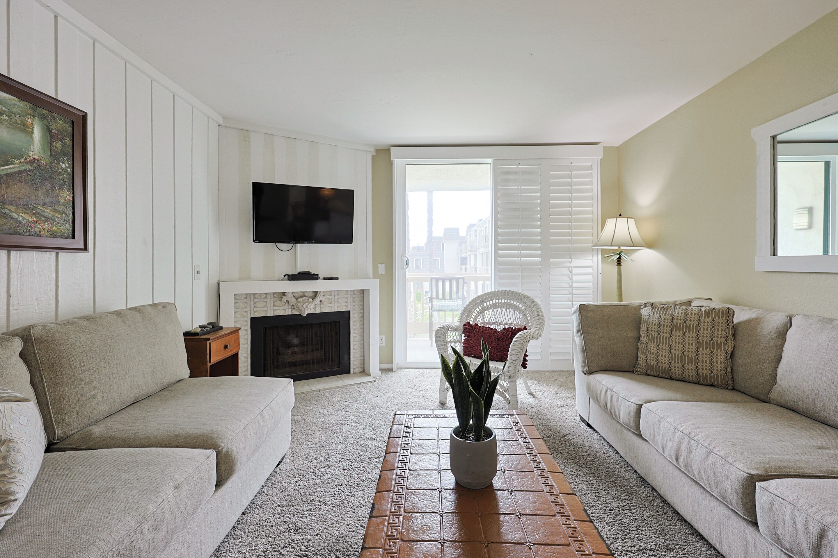 A living room with two sofas, a TV, a fireplace, and a balcony door.