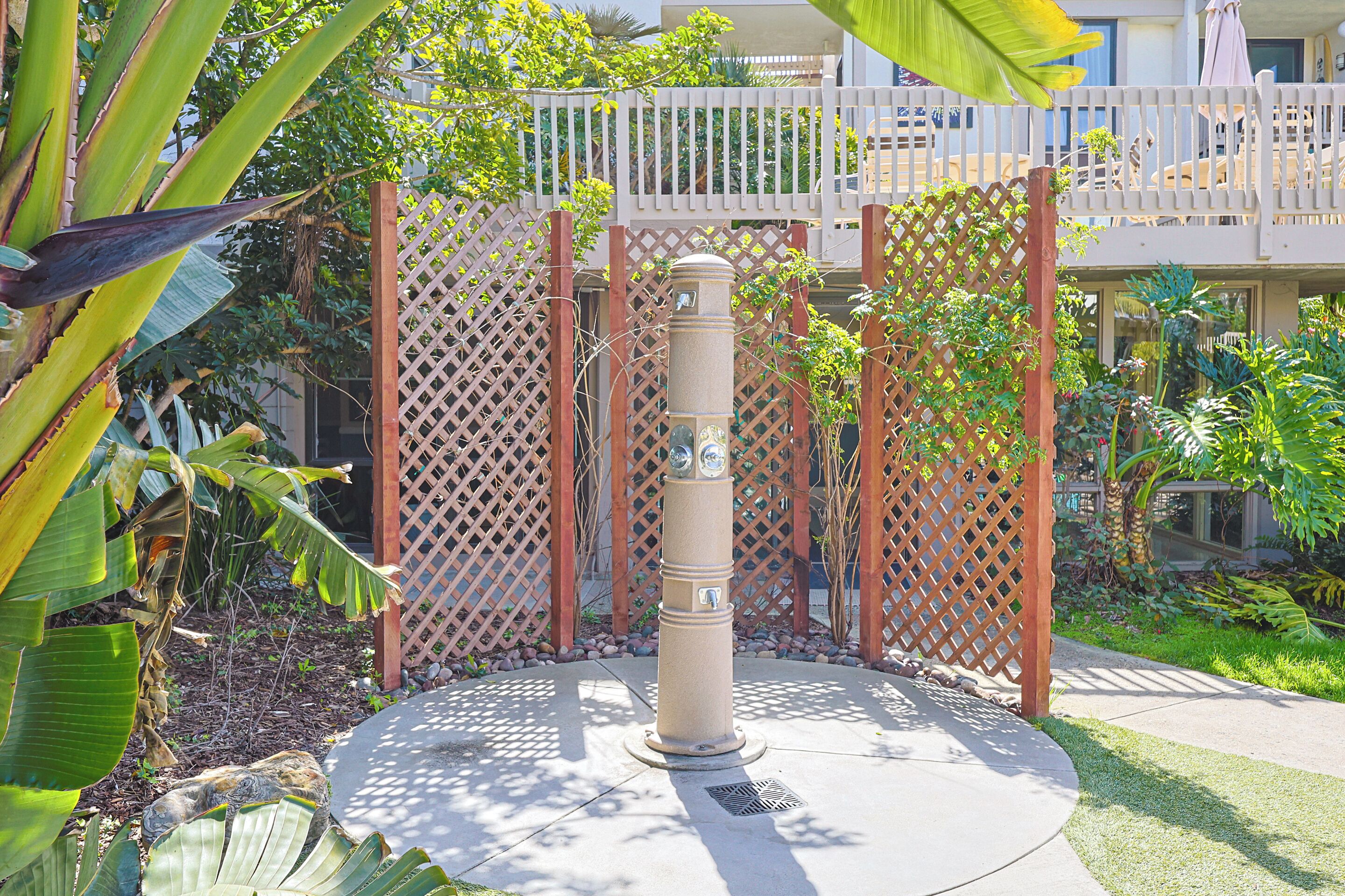 A concrete bollard with a circular base, surrounded by a wooden lattice fence and lush greenery.