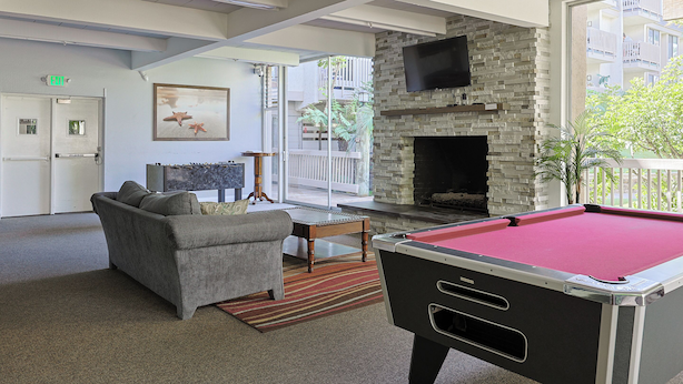 A pool table, a sofa, a fireplace, and a TV in a modern lounge area. - Whispering Waters: A Tranquil One-bedroom Retreat With Peek Ocean Views (Oceanside)