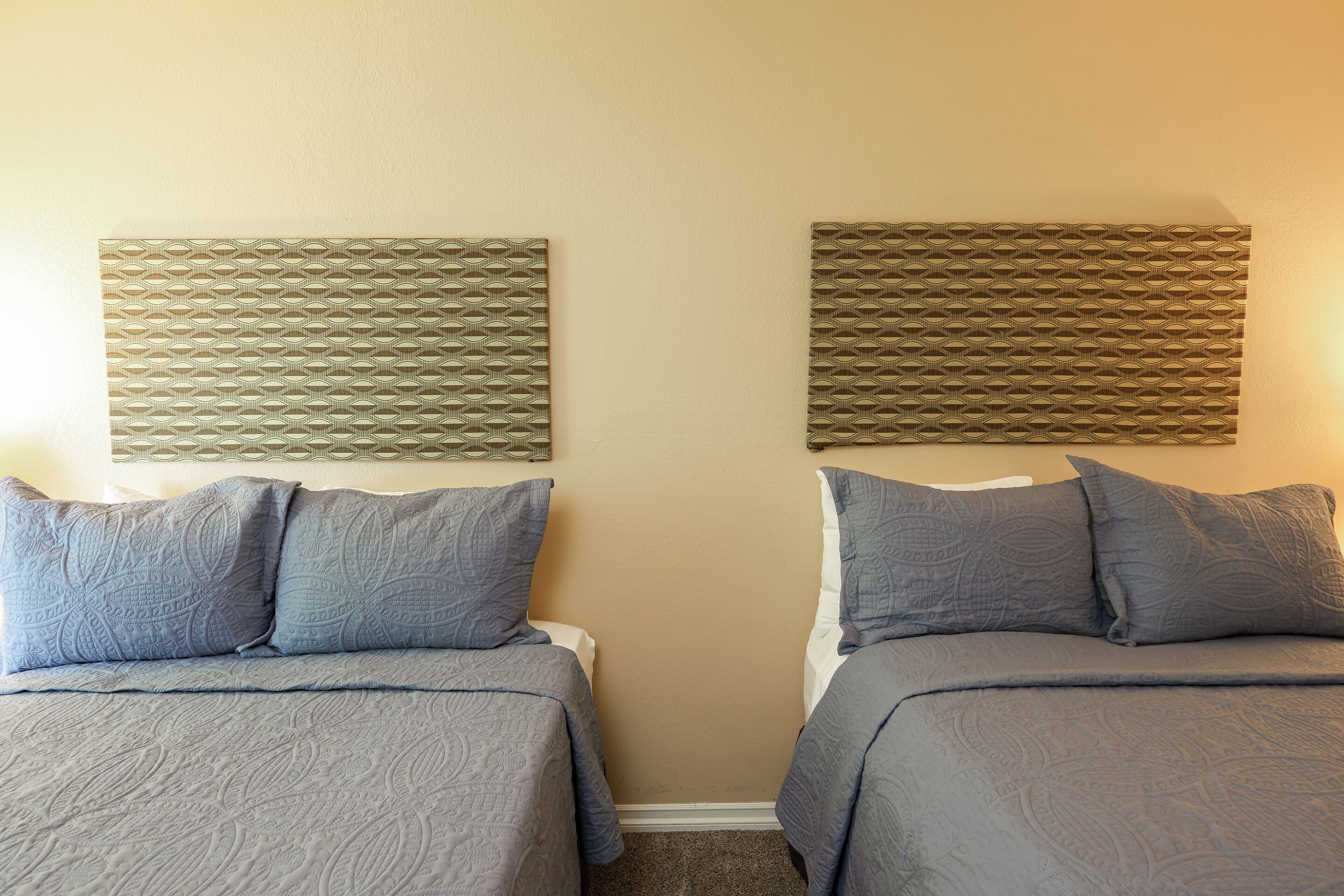 Een kamer met twee bedden, elk met een gestreept bedlaken en bijpassende kussens.