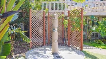 A concrete bollard with a circular base, surrounded by a wooden lattice fence and lush greenery.