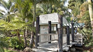 A small, rustic building with a sign reading "999 North Pacific" surrounded by lush greenery and a stone pathway. - Come Stay at G208 Secluded One Bedroom Unit Near the Ocean (Oceanside)
