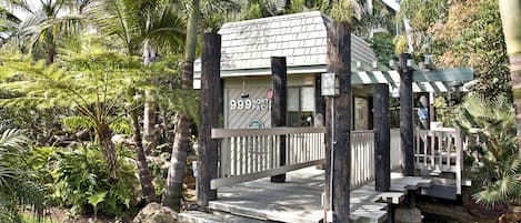 A small, rustic building with a sign reading "999 North Pacific" surrounded by lush greenery and a stone pathway.