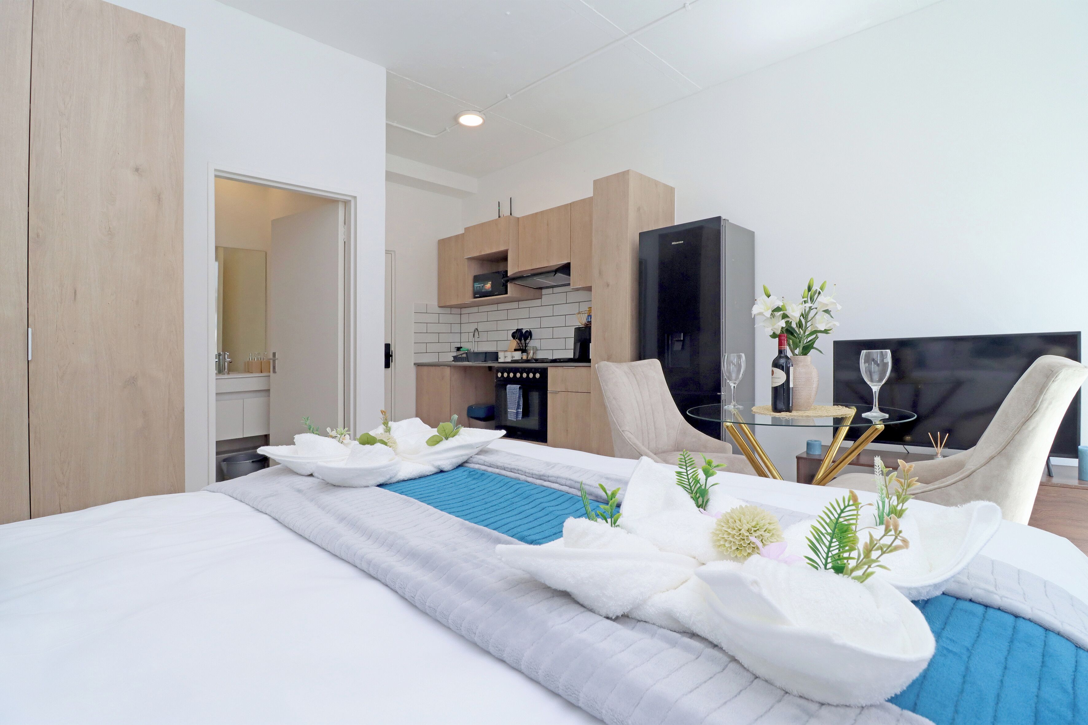 A hotel room with a bed, a small dining table, a sofa, and a television.