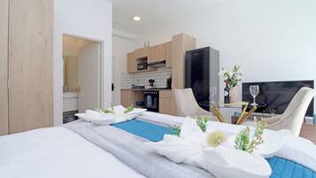 A hotel room with a bed, a small dining table, a sofa, and a television.