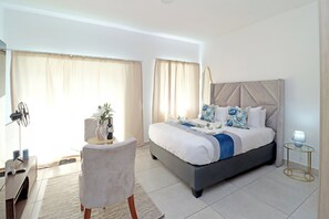 Una habitación de hotel con una cama, un escritorio, una silla y una mesita de noche.