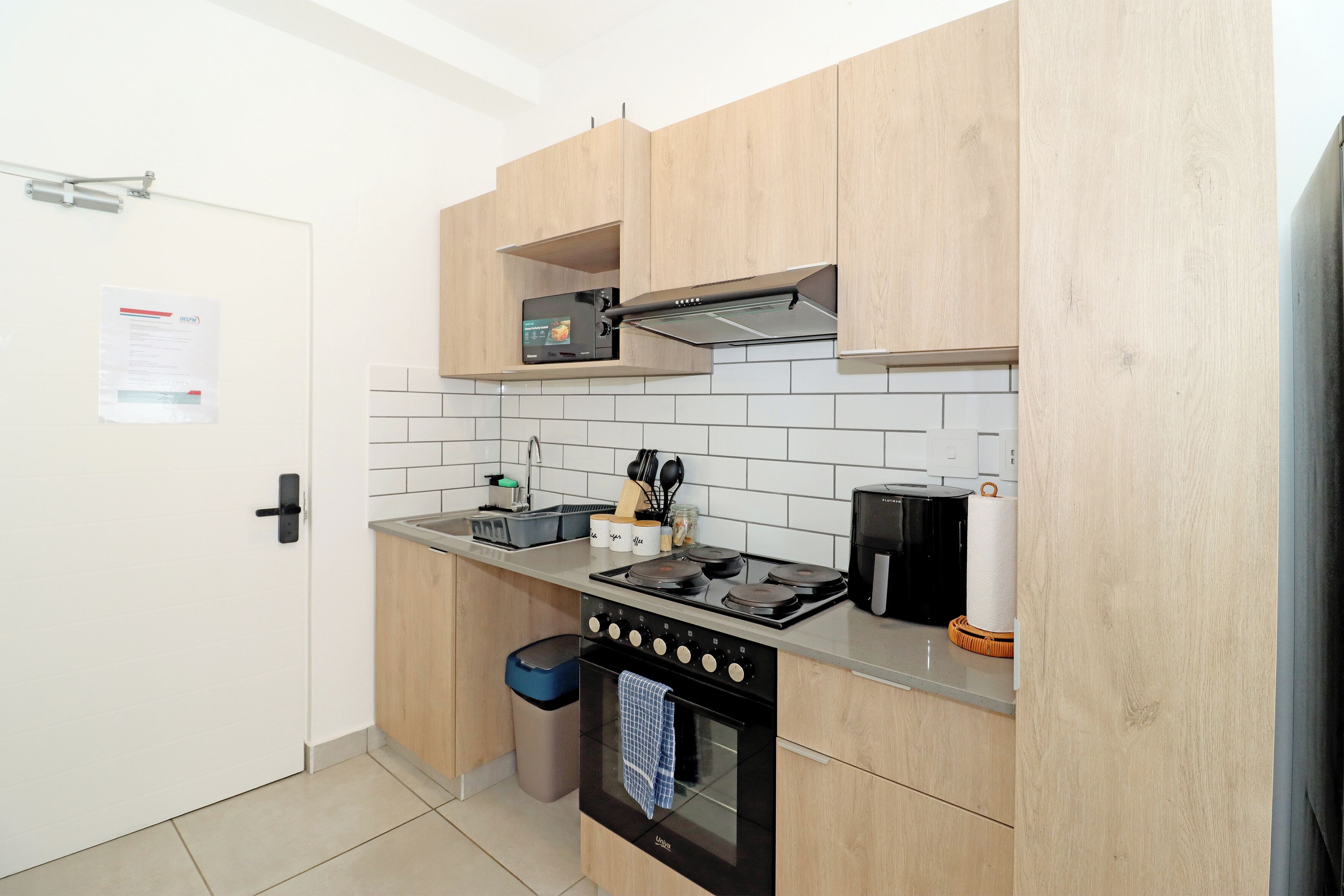 Una cucina compatta con fornelli, forno, microonde e un piccolo lavandino.