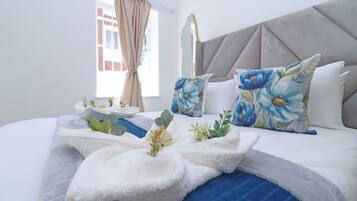 A neatly arranged hotel room with a bed, pillows, a bedside table, and a window with curtains.