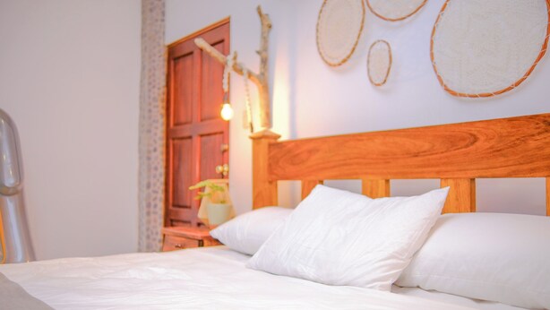 Ein Bett mit weißer Bettwäsche, einem Holz-Kopfteil und einem Nachttisch mit Lampe.