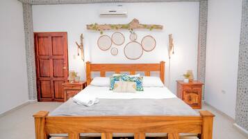 Un letto di legno con materasso bianco, due comodini, un armadio in legno, una parete con motivo in pietra e un condizionatore d'aria.