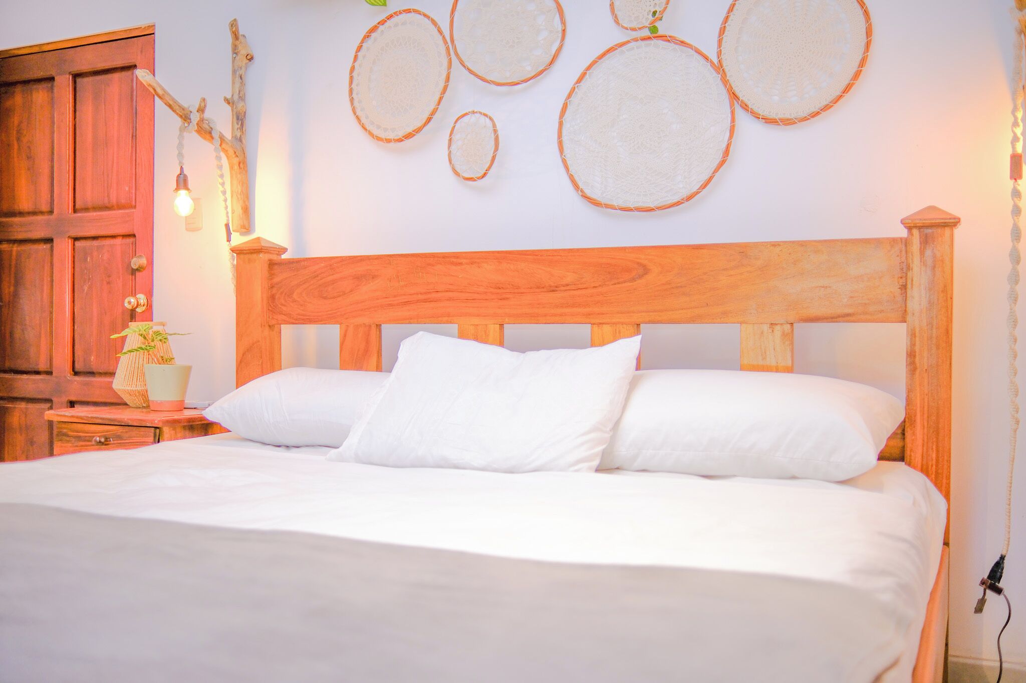 A bed with white bedding, a wooden headboard, and a nightstand with a lamp.