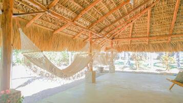A thatched-roof structure with a hammock and a concrete floor.