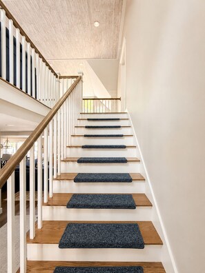 A staircase with wooden steps and white railings, leading to an upper floor. - Sebago Lake Estate, 300’ Frontage, Inside the State Park, Private Dock & Kayaks (Casco)