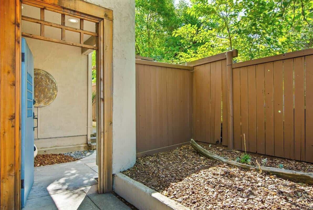 A wooden fence, a concrete pathway, and a garden bed with mulch.