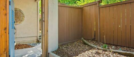 A wooden fence, a concrete pathway, and a garden bed with mulch.