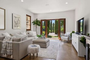 Ein modernes Wohnzimmer mit Sofa, Hocker und Fernseher.