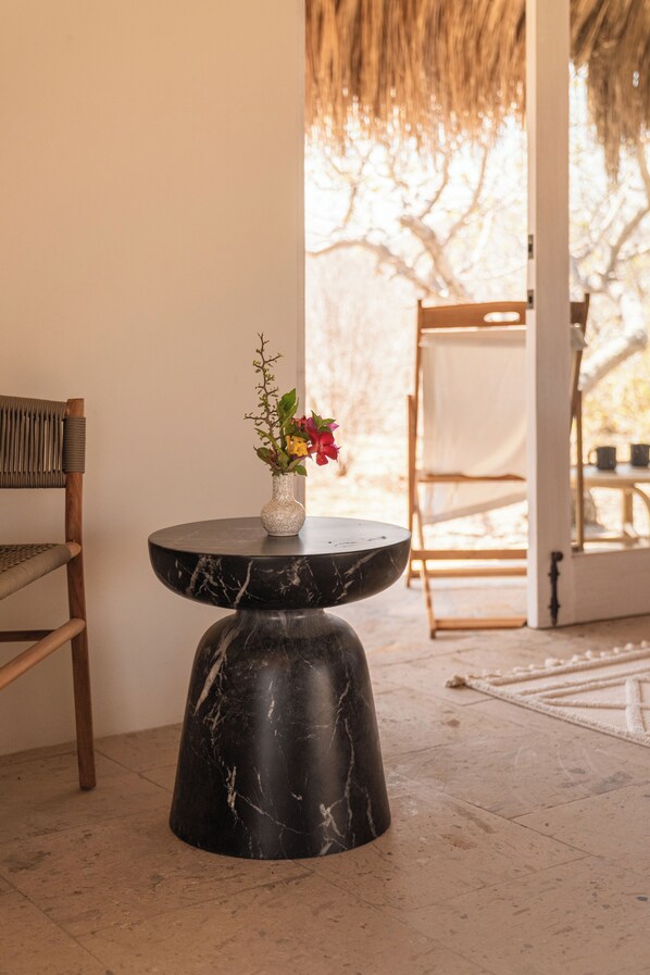 A room with a marble table, a chair, and a vase with flowers. - Bay Low House, a luxurious all-inclusive beachfront property. (La Ribera)