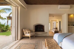 Ein Schlafzimmer mit Kamin, einem Bett, einer Sitzecke und Blick ins Freie.