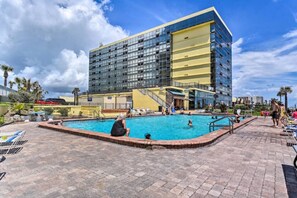 A hotel with a swimming pool, a covered area, and a modern building with multiple floors. - The Love Den | Oceanfront Couples Retreat (Daytona Beach)