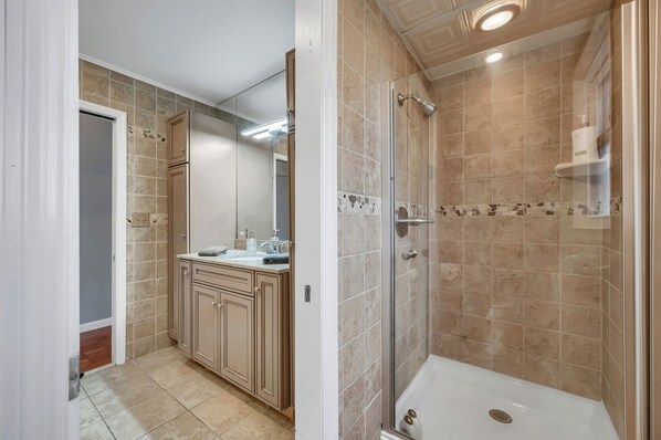 A bathroom with a shower, a sink with a mirror, and cabinets. - Hudson River views with pool and hot tub (Kingston)