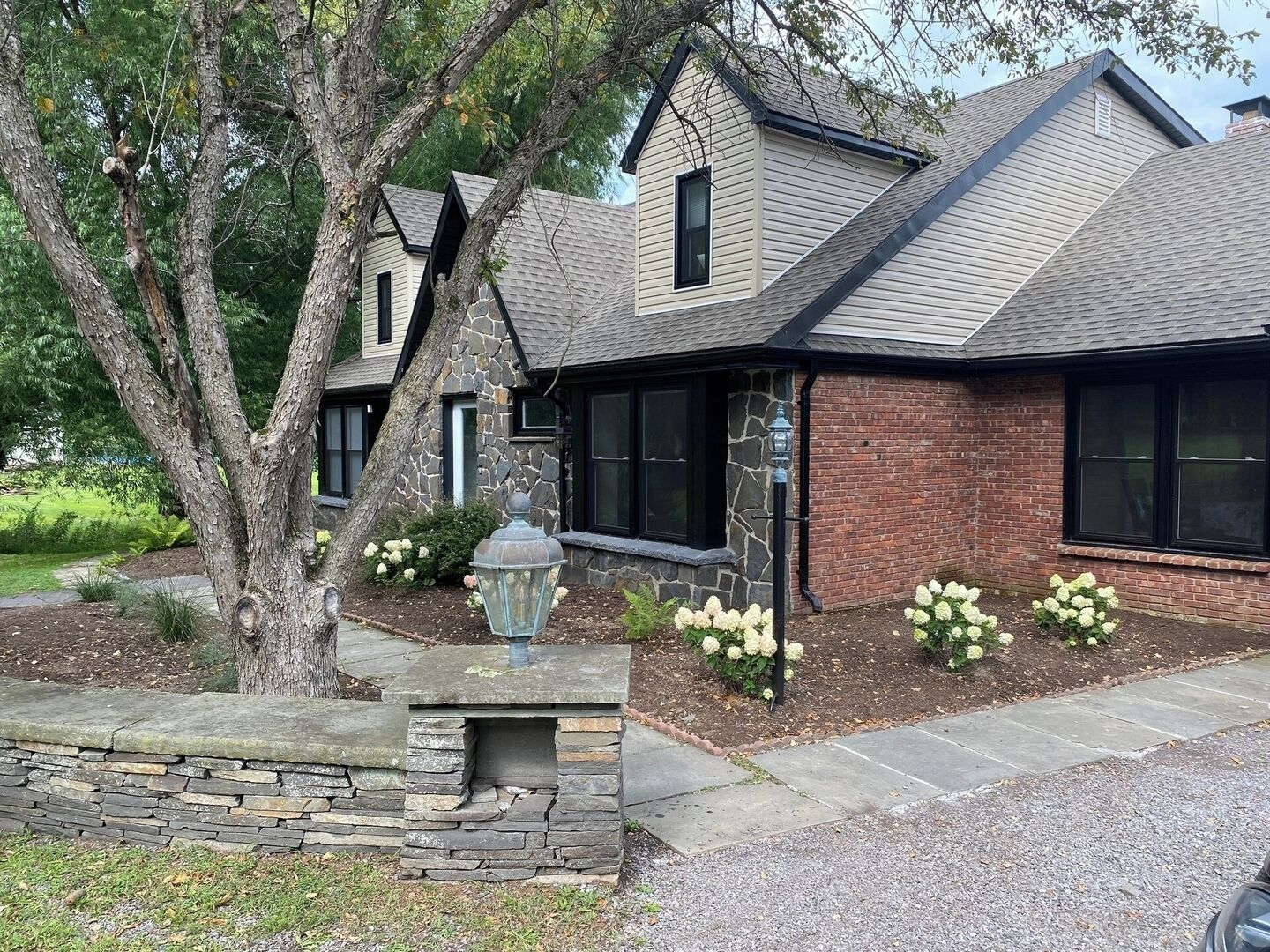 A two-story house with a stone foundation, a brick exterior, and a sloped roof.