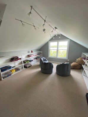 A room with a sloped ceiling, white walls, and a large window. There are shelves with toys and books, and two bean bags on the floor. - Hudson River views with pool and hot tub (Kingston)