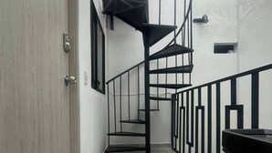 Eine Wendeltreppe mit schwarzen Geländern und einer Holztür links.
