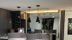 Ein modernes Interieur mit einer abgetrennten Sitzgruppe, Pendelleuchten und einem sichtbaren Kunstwerk an der Wand.